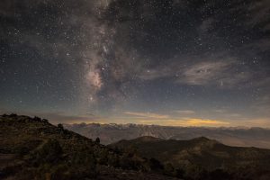 Landscape picture of the tops of mountains and the night sky filled with stars.